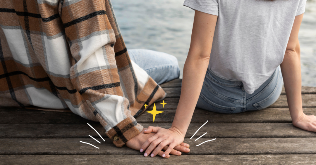 Two people holding hands on a wooden surface, showing how a small moment can lead to falling for someone you barely talk to