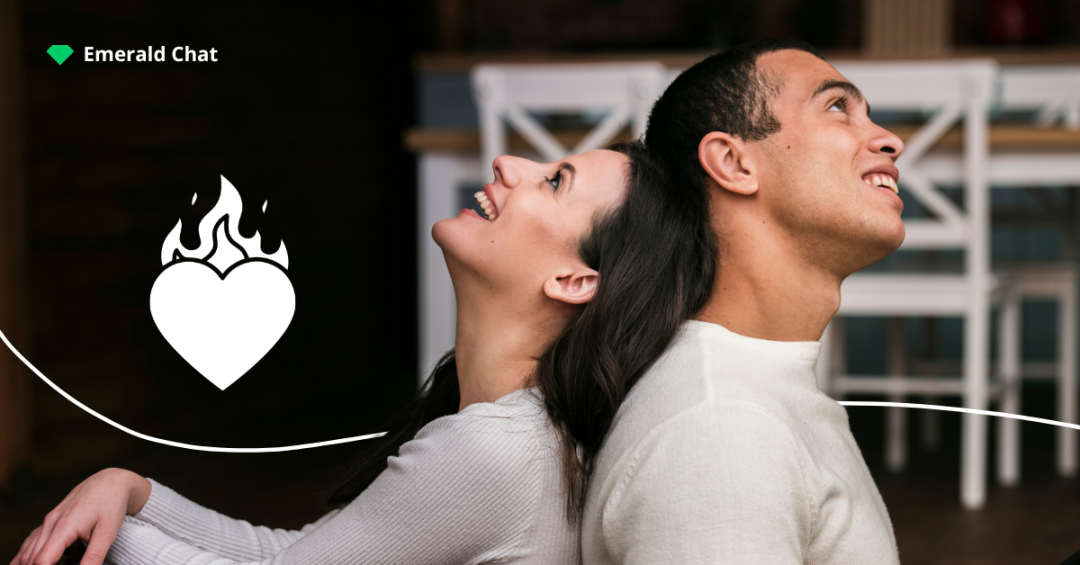 Two people leaning back to back and smiling, representing the quiet intensity of falling for someone you barely talk to